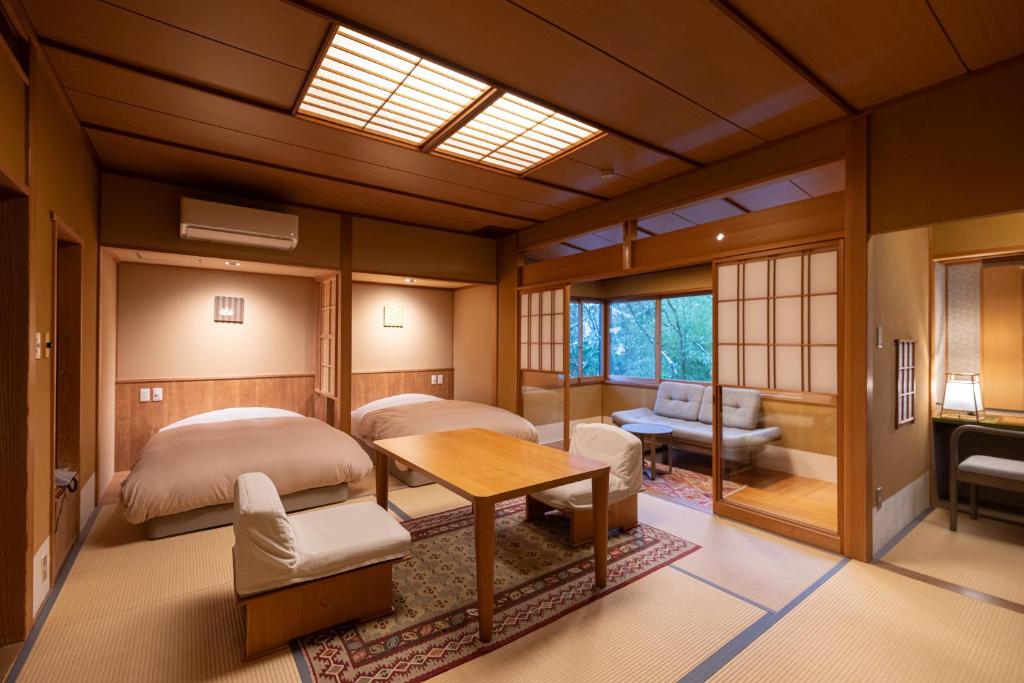 une chambre avec deux lits et une table dans une pièce dans l'établissement Shaga-no-Sato Yumeya, à Niigata