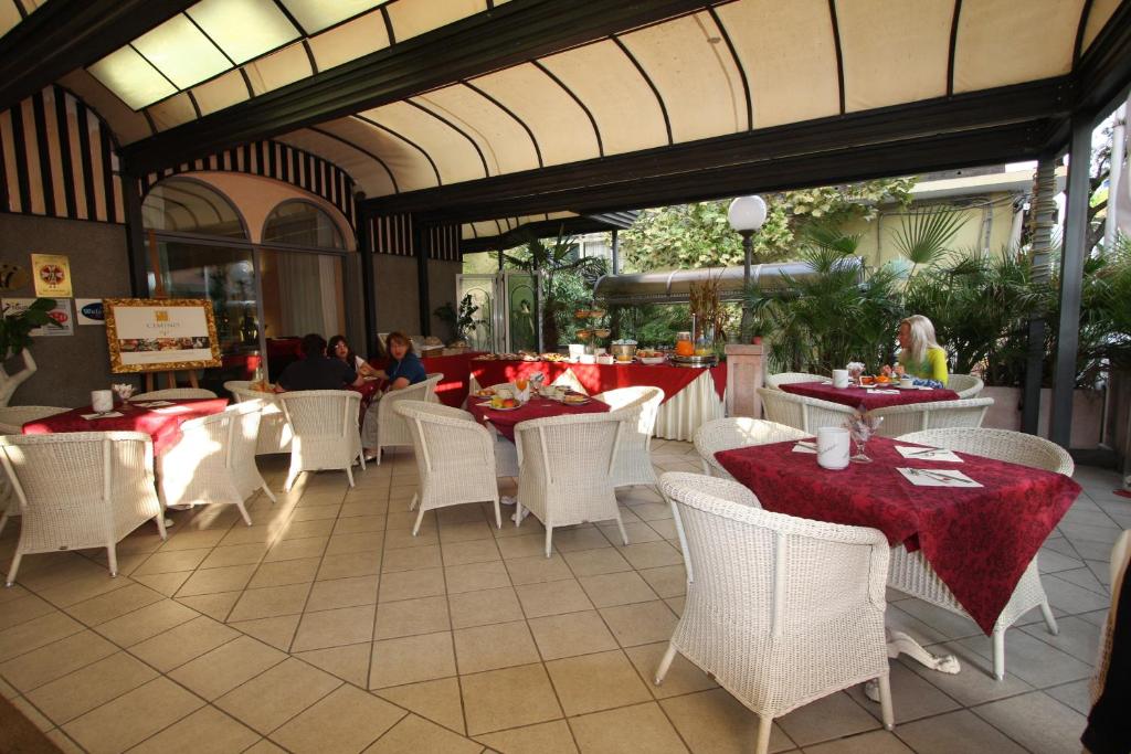 un restaurant avec des tables blanches, des chaises et des personnes blanches dans l'établissement Hotel Vienna Ostenda e Ristorante il Danubio, à Rimini