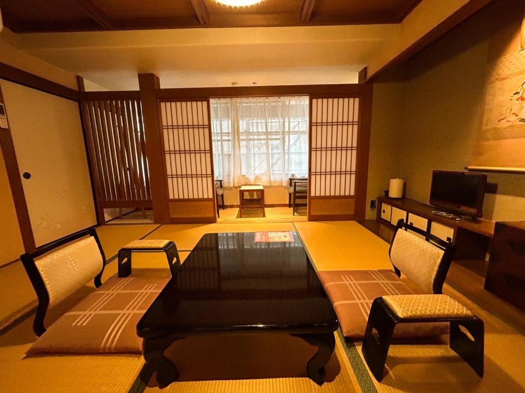 une pièce avec une table, des chaises et une télévision dans l'établissement Sangai Ryokan, à Gotsu