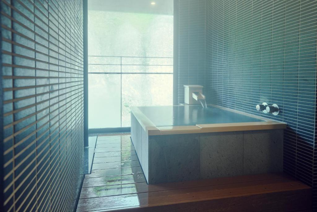 une salle de bain avec baignoire et une grande fenêtre dans l'établissement Sansuiso Tsuchiyu Spa, à Fukushima