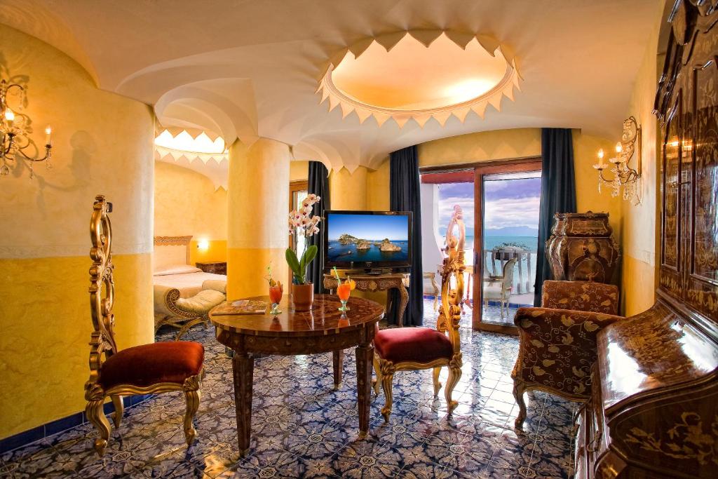 un salon avec une table, des chaises et une télévision dans l'établissement Strand Hotel Delfini, à Ischia