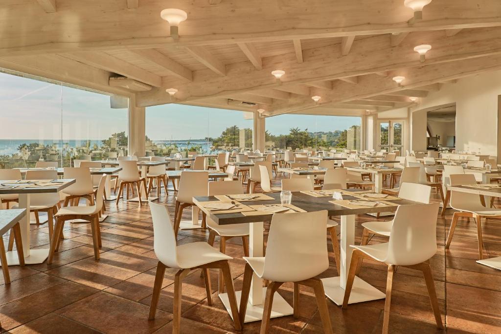 un restaurant avec tables et chaises avec vue dans l'établissement Club Esse Roccaruja, à Stintino