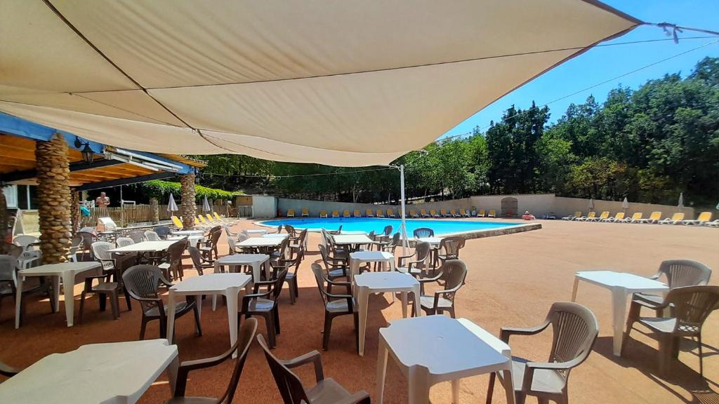 un restaurant en plein air avec des tables et des chaises ainsi qu'une piscine dans l'établissement Camping Naturiste Tikayan Petit Arlane, à Valensole
