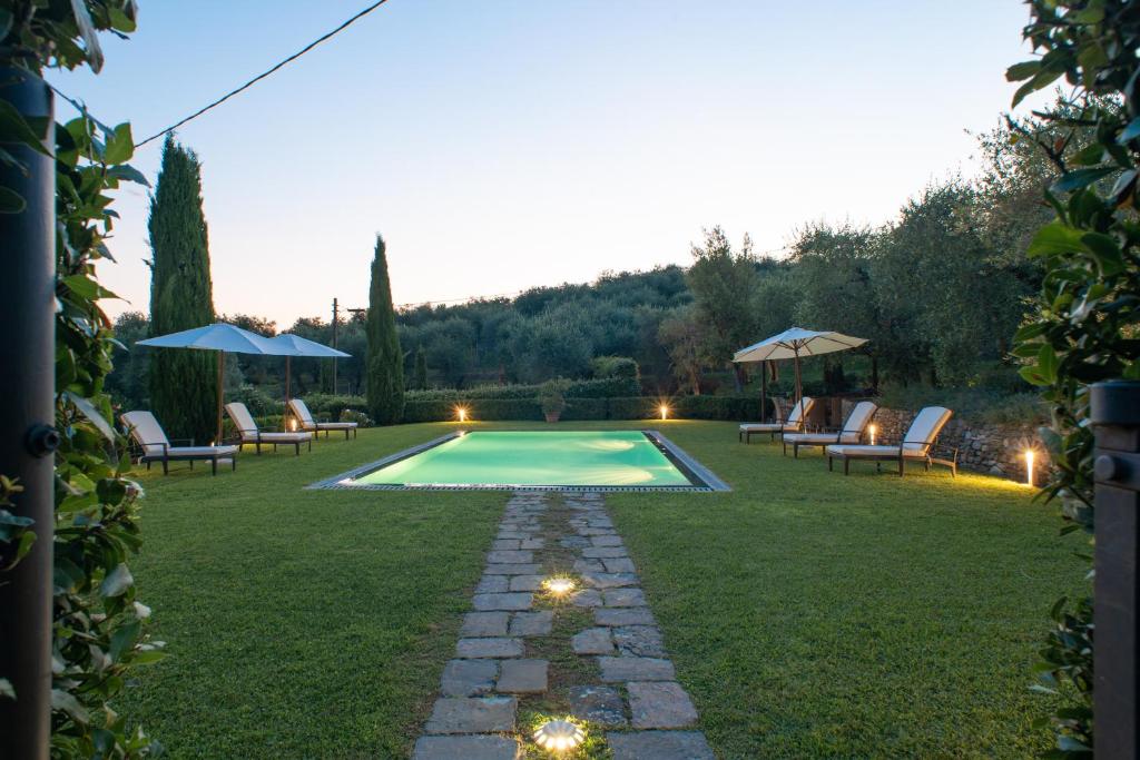 une cour avec une piscine entourée de chaises et d'une pelouse dans l'établissement Villa Cassandori by Mmega, à Lucques