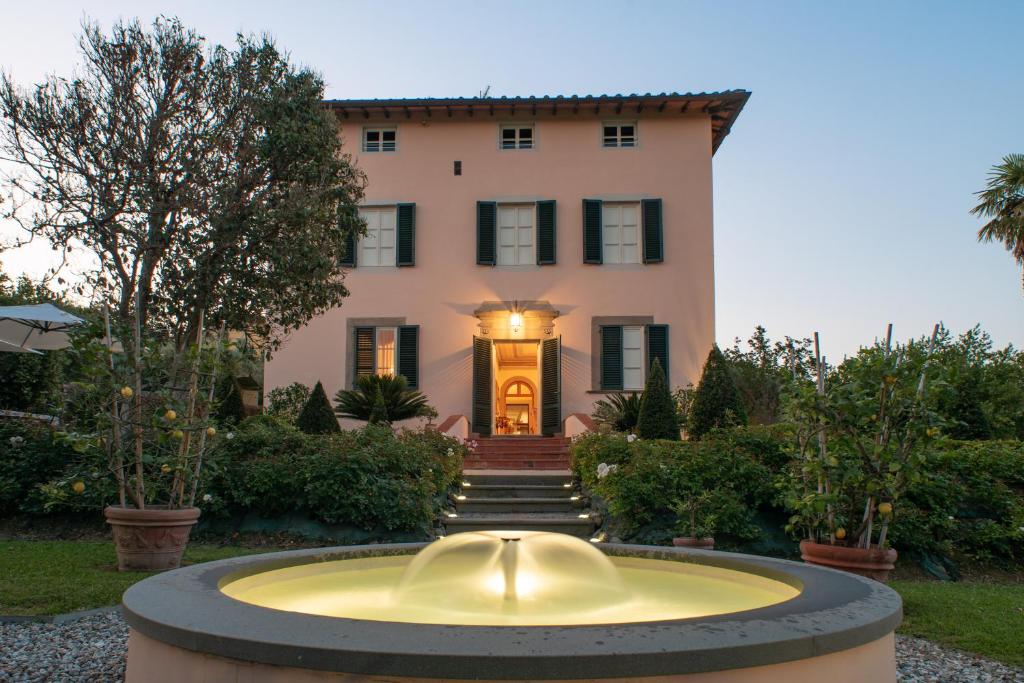 une grande maison avec une fontaine en face de celle-ci dans l'établissement Villa Cassandori by Mmega, à Lucques