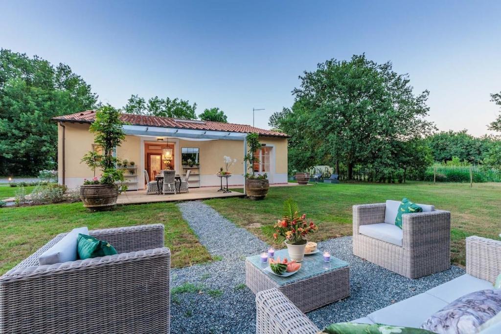 une arrière-cour avec des chaises en osier et une maison dans l'établissement Villa Bassotta, a Charming Cottage, à Lucques