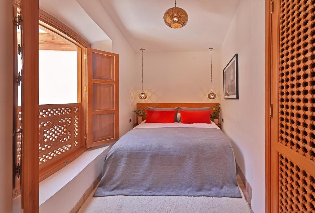 une chambre avec un lit avec des oreillers rouges et une fenêtre dans l'établissement RIAD THE MILESTONE, à Marrakech
