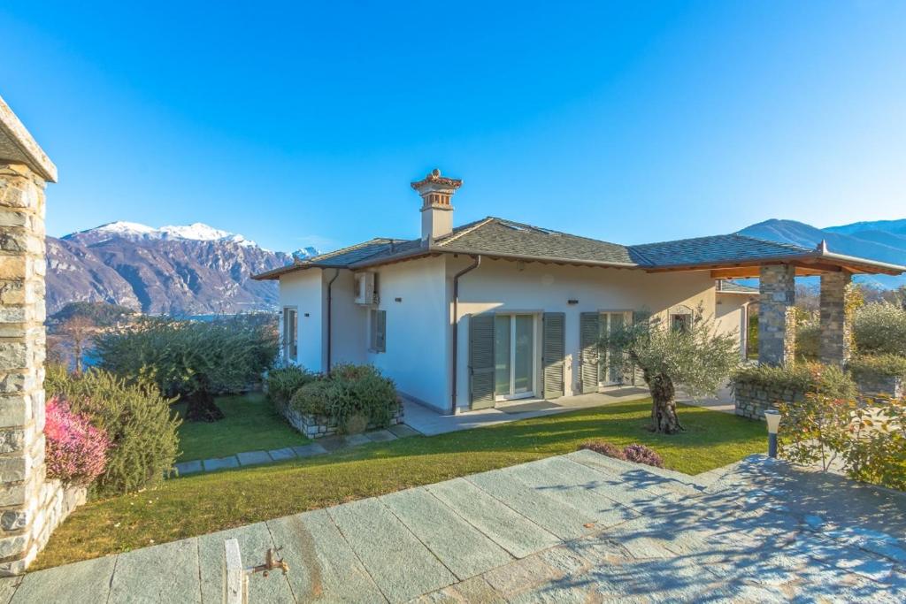 une maison blanche avec des montagnes en arrière-plan dans l'établissement Villa Rogaro Corinna, à Griante Cadenabbia