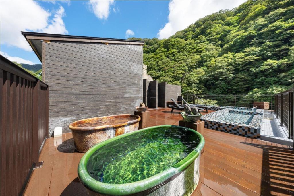 une grande baignoire verte installée au-dessus d'une terrasse dans l'établissement Hakkei, à Maniwa 37 autres photos