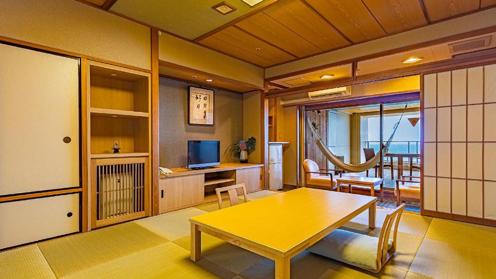 un salon avec une table jaune et une télévision dans l'établissement Hamanoyu, à Higashiizu