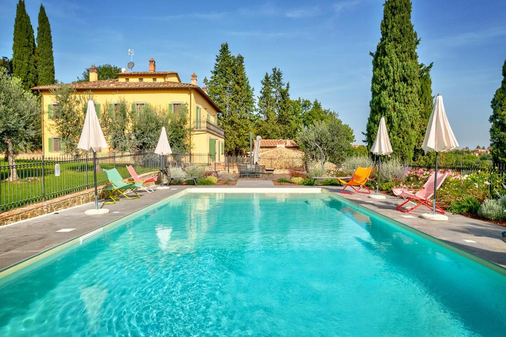 - une piscine avec des chaises et des parasols en face d'une maison dans l'établissement Villa Maria, à Monte San Savino