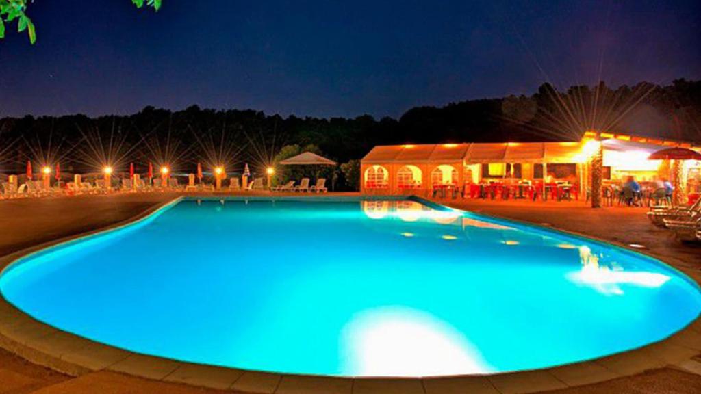- une grande piscine bleue la nuit dans l'établissement Camping Naturiste Tikayan Petit Arlane, à Valensole