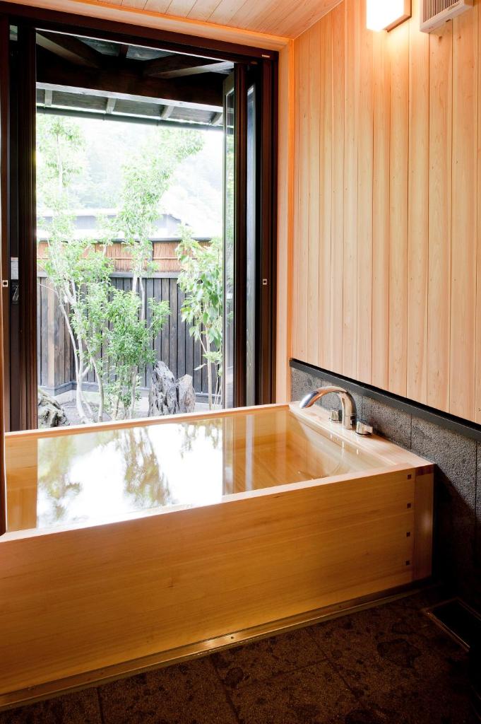 une baignoire en bois dans une pièce avec une fenêtre dans l'établissement Yamakikan, à Naganohara