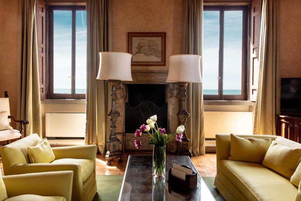 un salon avec une cheminée et une table avec des fleurs dessus dans l'établissement La Posta Vecchia Hotel, à Ladispoli