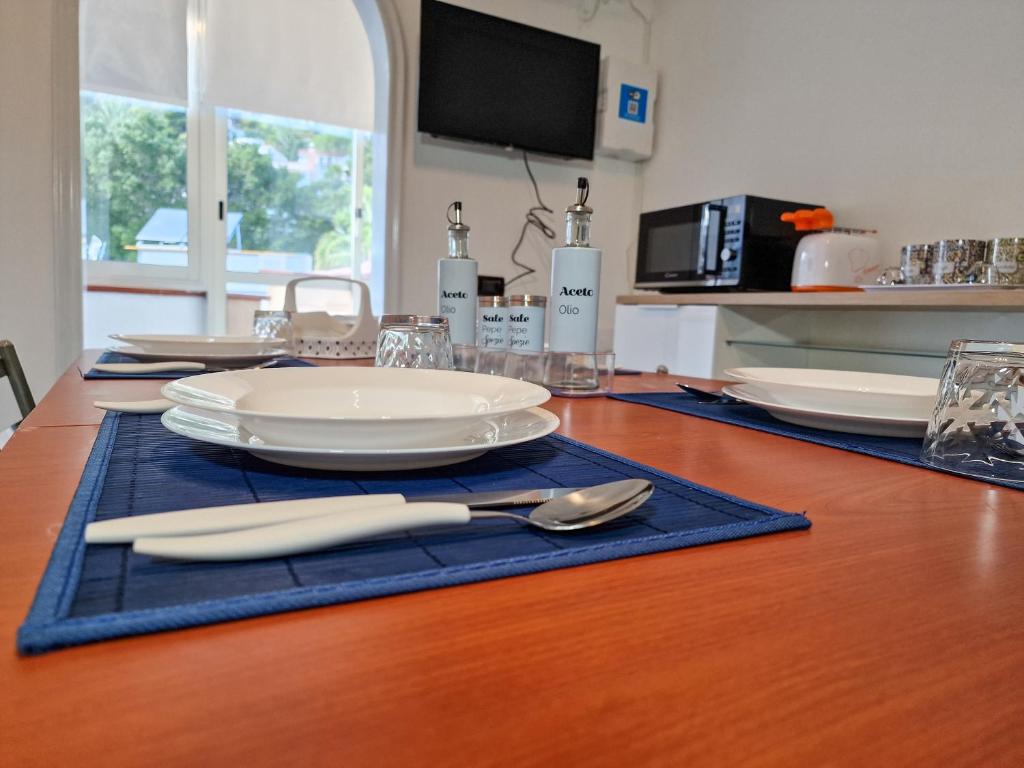 une table en bois avec des assiettes et des ustensiles dessus dans l'établissement ASHUR310 RESIDENCE MONDELLO, à Mondello