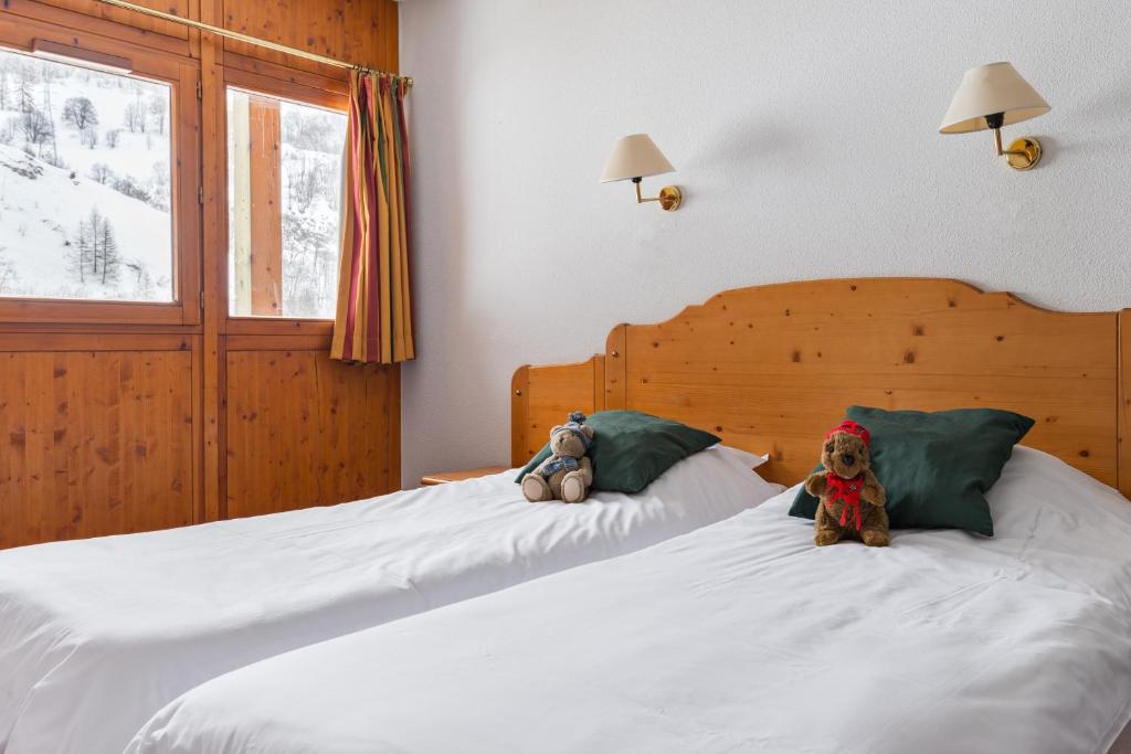 deux animaux farcis assis au-dessus d'un lit dans l'établissement Lagrange Vacances Chalets du Galibier, à Valloire