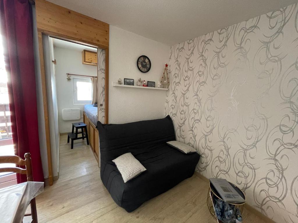 un salon avec un canapé noir dans une pièce dans l'établissement Petit appartement Labellisé Les 2 Alpes résidence Arc en Ciel télésiège Petite Aiguille, à Les Deux Alpes