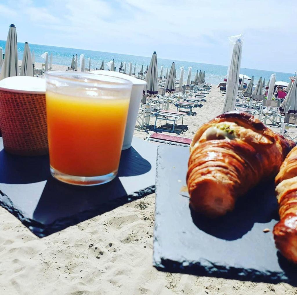 une assiette de pain et un verre de jus d'orange sur la plage dans l'établissement lidodubaihotel, à Marina di Ginosa