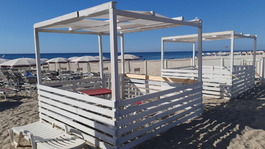 un bâtiment sur la plage avec des chaises et des parasols dans l'établissement lidodubaihotel, à Marina di Ginosa