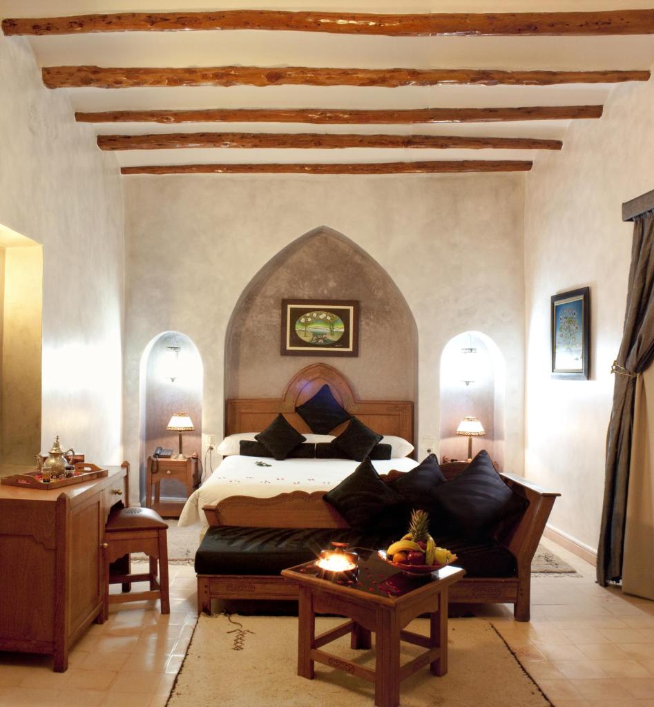 une chambre avec un grand lit et une table dans l'établissement Palais Des Remparts, à Essaouira