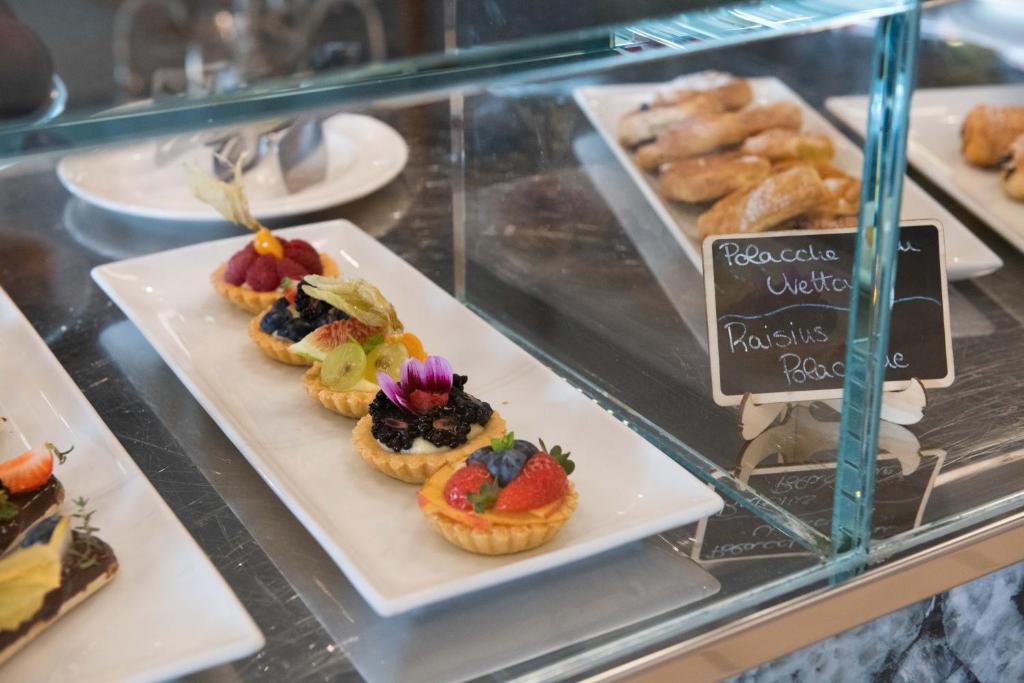 une vitrine avec des muffins et des pâtisseries sur les assiettes dans l'établissement Kiss Beachfront Hotel & Restaurant, à Cervia