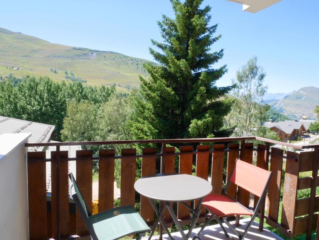 une table et des chaises sur un balcon avec un arbre dans l'établissement appartement ski au pied, à Les Deux Alpes