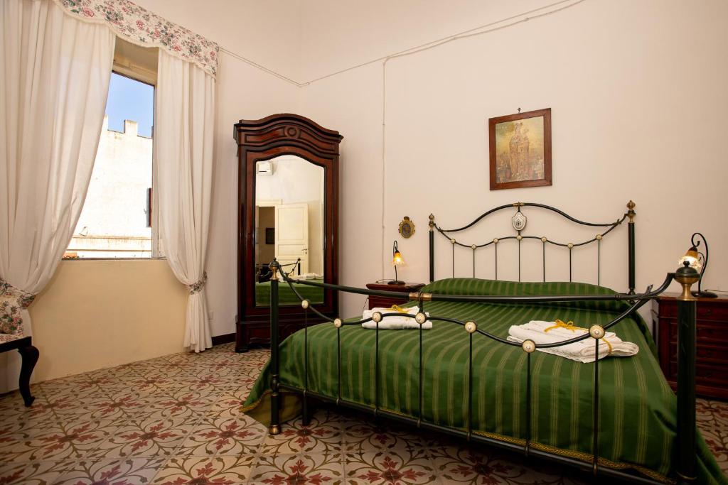 - une chambre avec un lit vert et un miroir dans l'établissement Antica Fortezza Villa Fontana, à Valderice