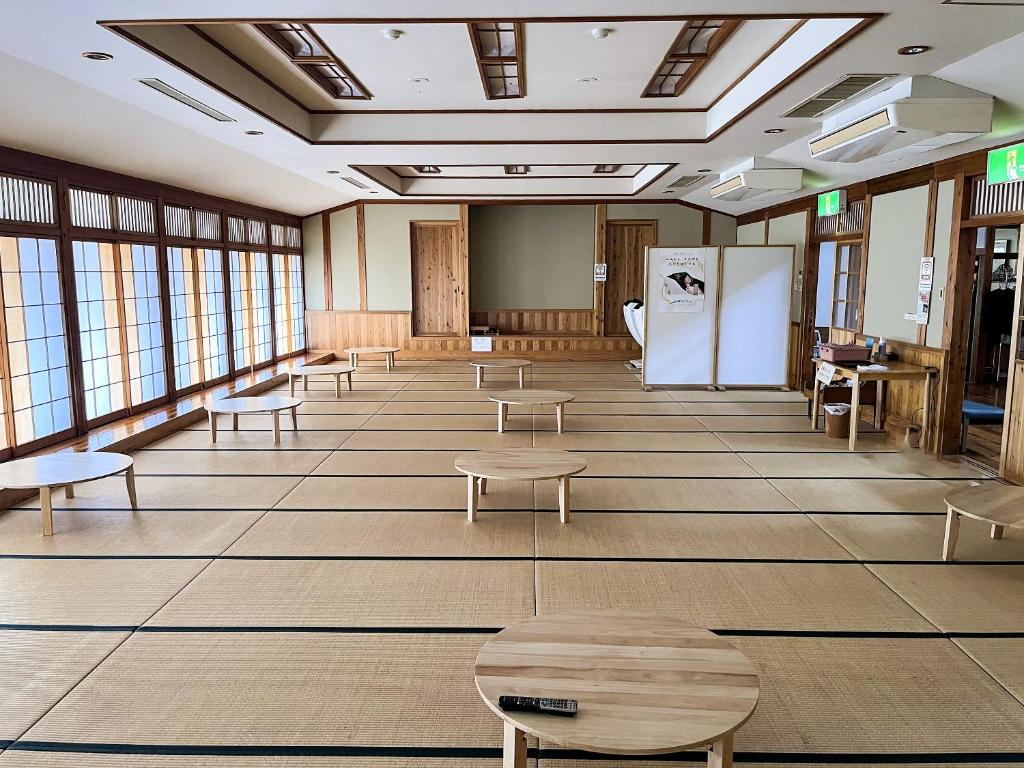 une grande pièce avec des tables, des bancs et des fenêtres dans l'établissement 津川温泉 清川高原保養センター, à Aga