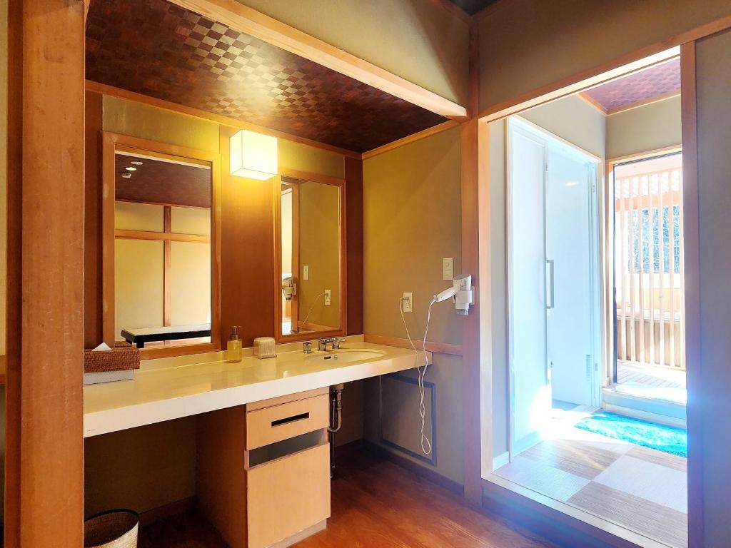 une salle de bain avec un lavabo et un grand miroir dans l'établissement Kose Onsen, à Karuizawa 66 autres photos