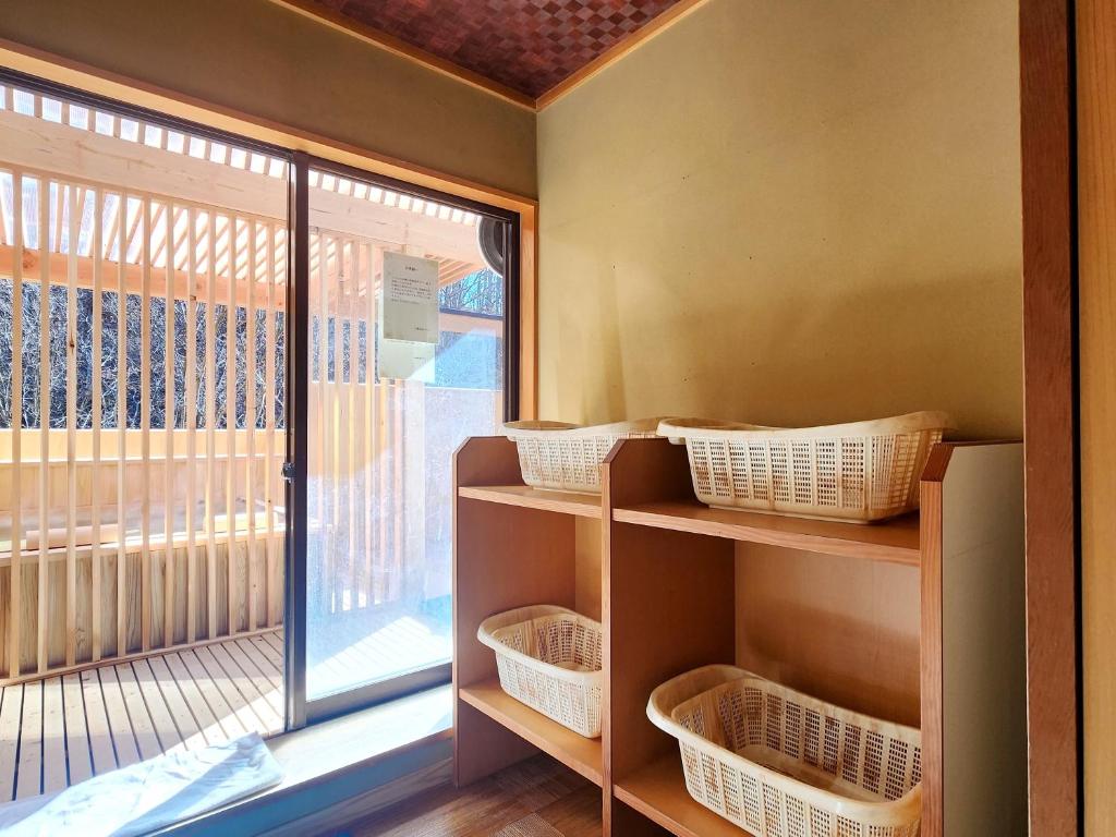 une chambre avec des paniers sur des étagères à côté d'une fenêtre dans l'établissement Kose Onsen, à Karuizawa
