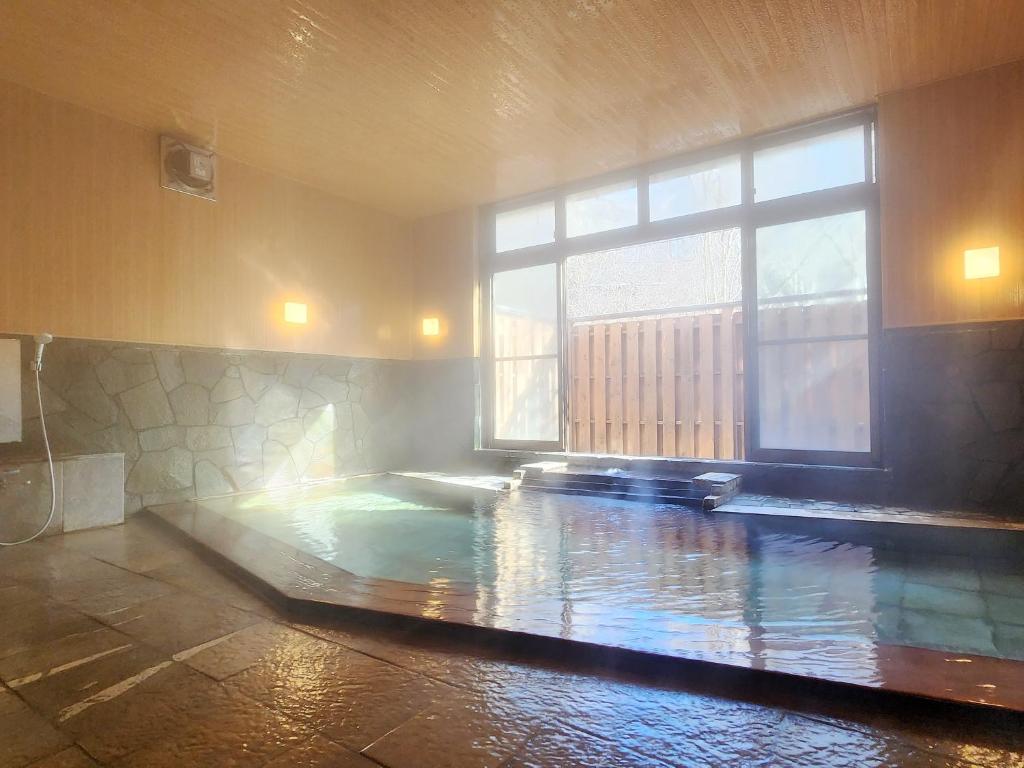 - une piscine dans une chambre dotée d'une grande fenêtre dans l'établissement Kose Onsen, à Karuizawa