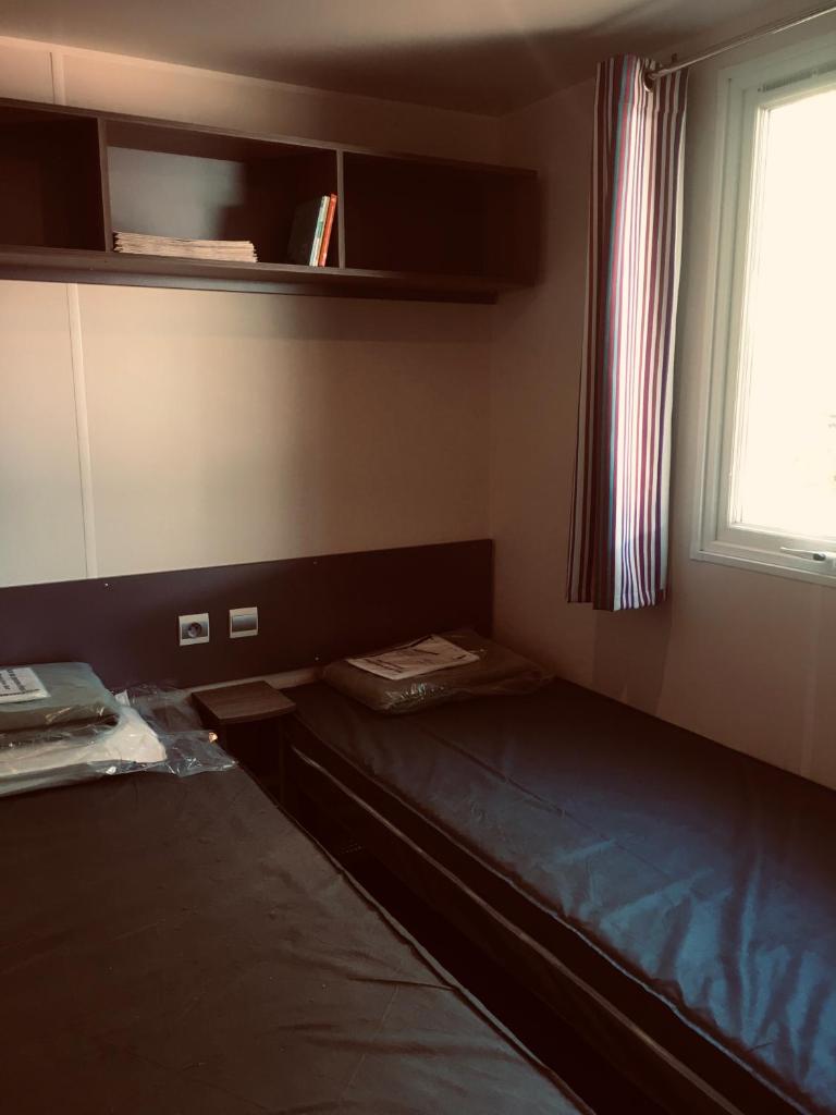 une petite chambre avec deux lits et une fenêtre dans l'établissement parc des 7 fonts, à Agde