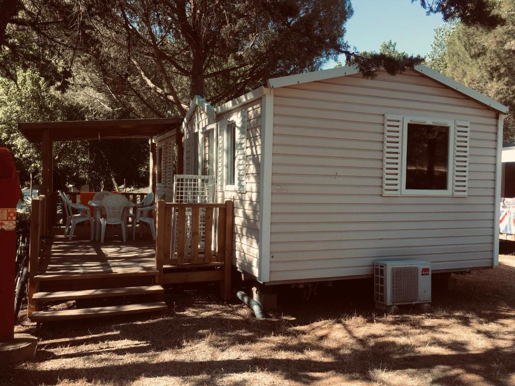 Un petit hangar blanc avec une véranda et une terrasse est disponible. dans l'établissement parc des 7 fonts, à Agde