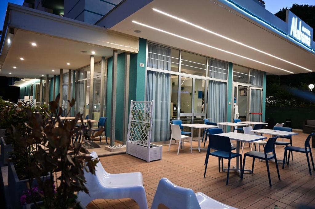 une terrasse avec des tables et des chaises devant un bâtiment dans l'établissement Hotel Alabama, à Riccione