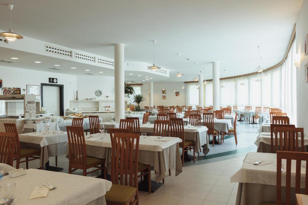 une salle à manger avec des tables et des chaises blanches et un restaurant dans l'établissement Hotel Santo Stefano, à Bibione
