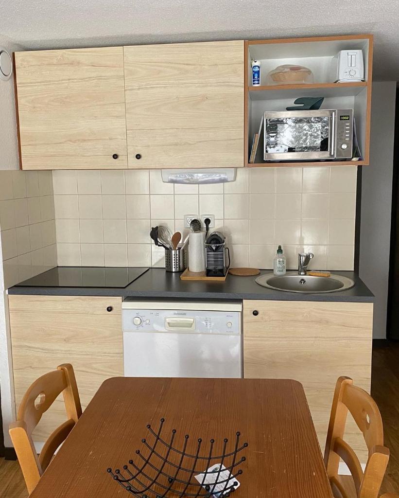 une petite cuisine avec une table et un micro-ondes dans l'établissement Au pays des marmottes Appartement 6 personnes plein sud sans vis à vis avec terrasse, à Chamrousse 23 autres photos