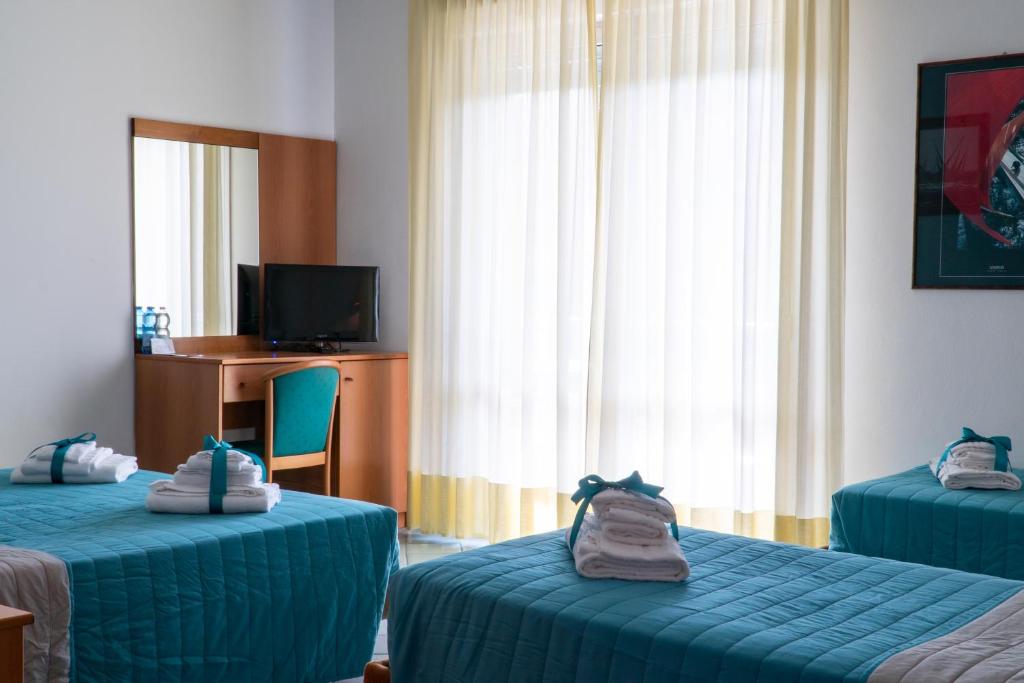 une chambre d'hôtel avec deux lits et une télévision dans l'établissement Hotel Alisei, à Lignano Sabbiadoro