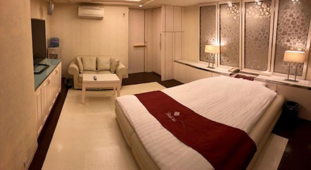 une chambre avec un lit et une chaise dans une pièce dans l'établissement Prime Hotel Fulula プライムホテル フルーラ, à Osaka