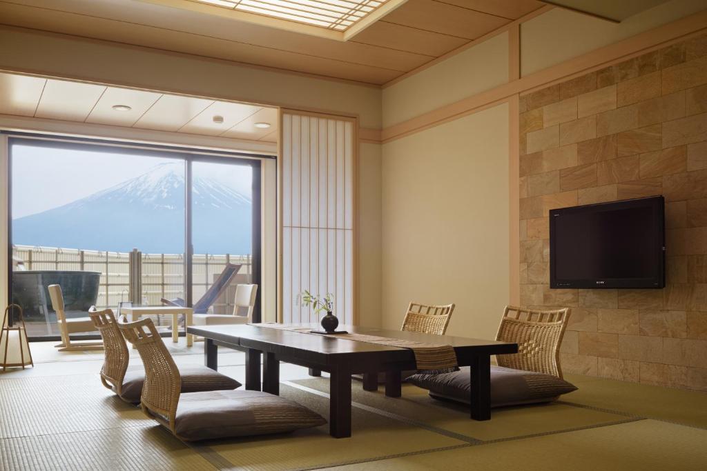 une salle à manger avec une table, des chaises et une télévision dans l'établissement Fujikawaguchiko Onsen Konanso, à Fujikawaguchiko