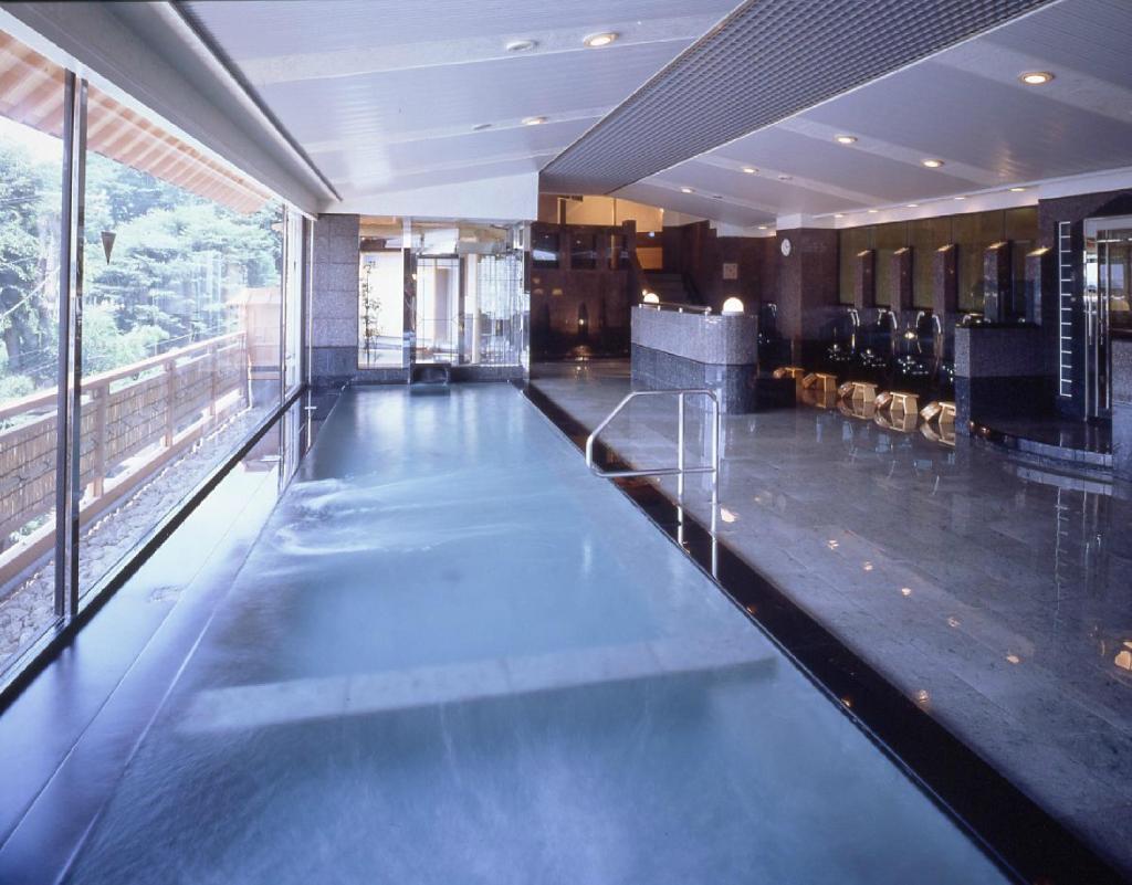 une grande piscine dans un immeuble avec une grande fenêtre dans l'établissement Fujikawaguchiko Onsen Konanso, à Fujikawaguchiko