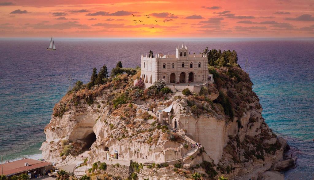 un château sur une falaise dans l'océan au coucher du soleil dans l'établissement ValGiuSi Resort, à Capo Vaticano
