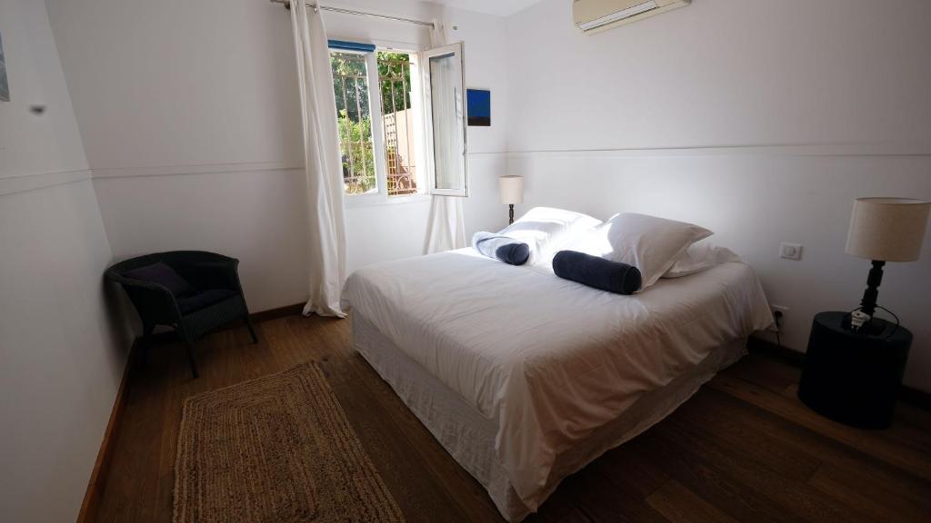 une chambre avec un lit blanc avec des oreillers et une fenêtre dans l'établissement Bastide le Petit Clos - les 2 Gîtes, à Perpignan
