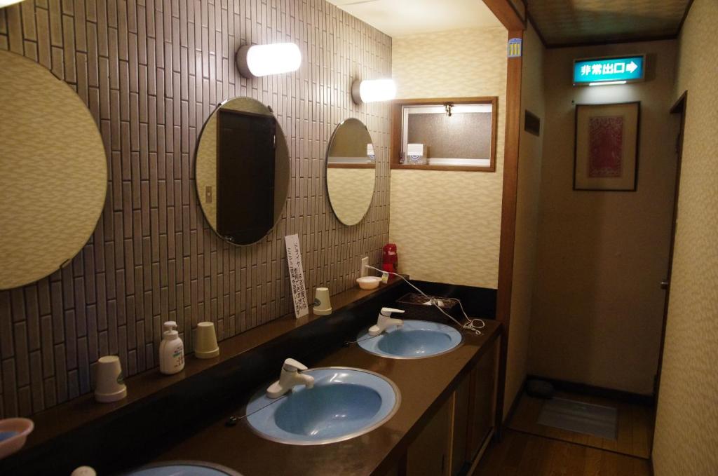 une salle de bain avec deux lavabos et deux miroirs dans l'établissement Ryokan Takayama, à Takayama 23 autres photos