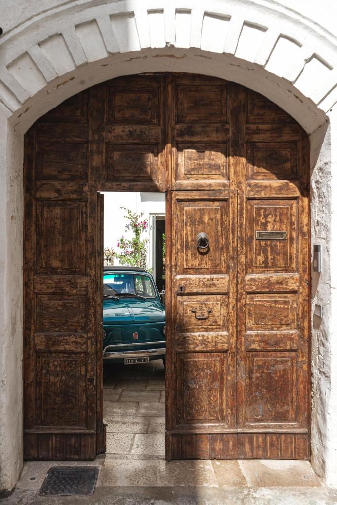 une grande porte en bois avec une voiture derrière elle dans l'établissement Casa a Corte, Nardò, à Nardò