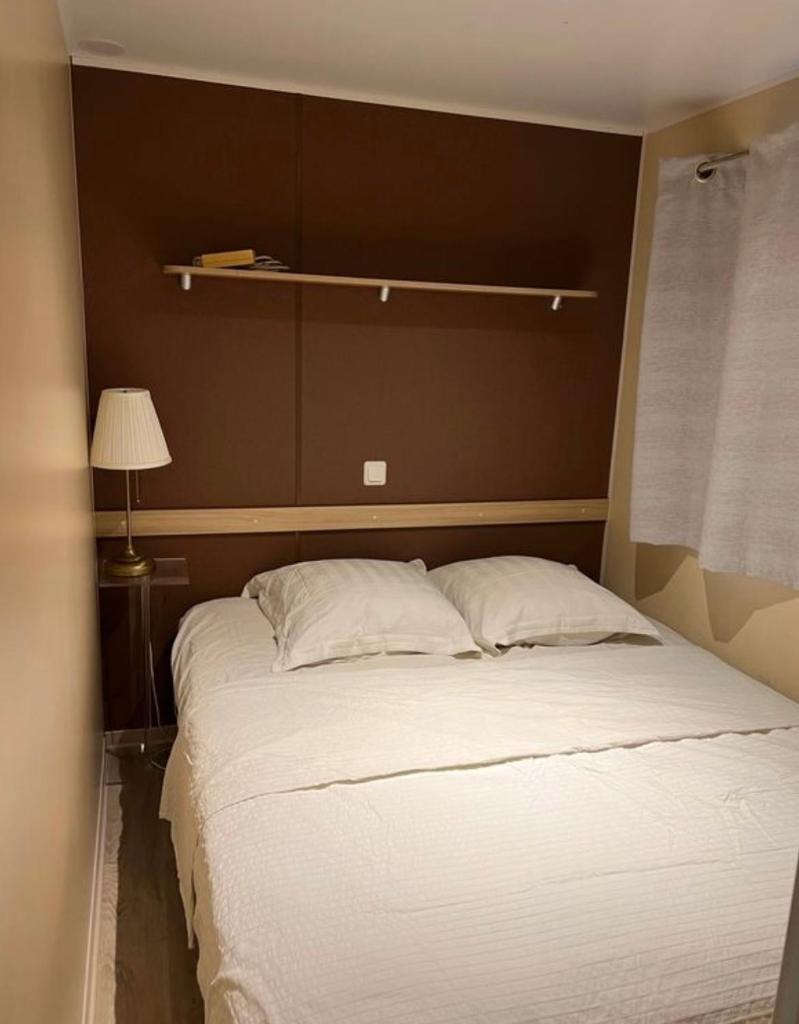 - un grand lit avec des draps et des oreillers blancs dans une chambre dans l'établissement Mobil-Home des Iscles, à La Roque-dʼAnthéron 5 autres photos