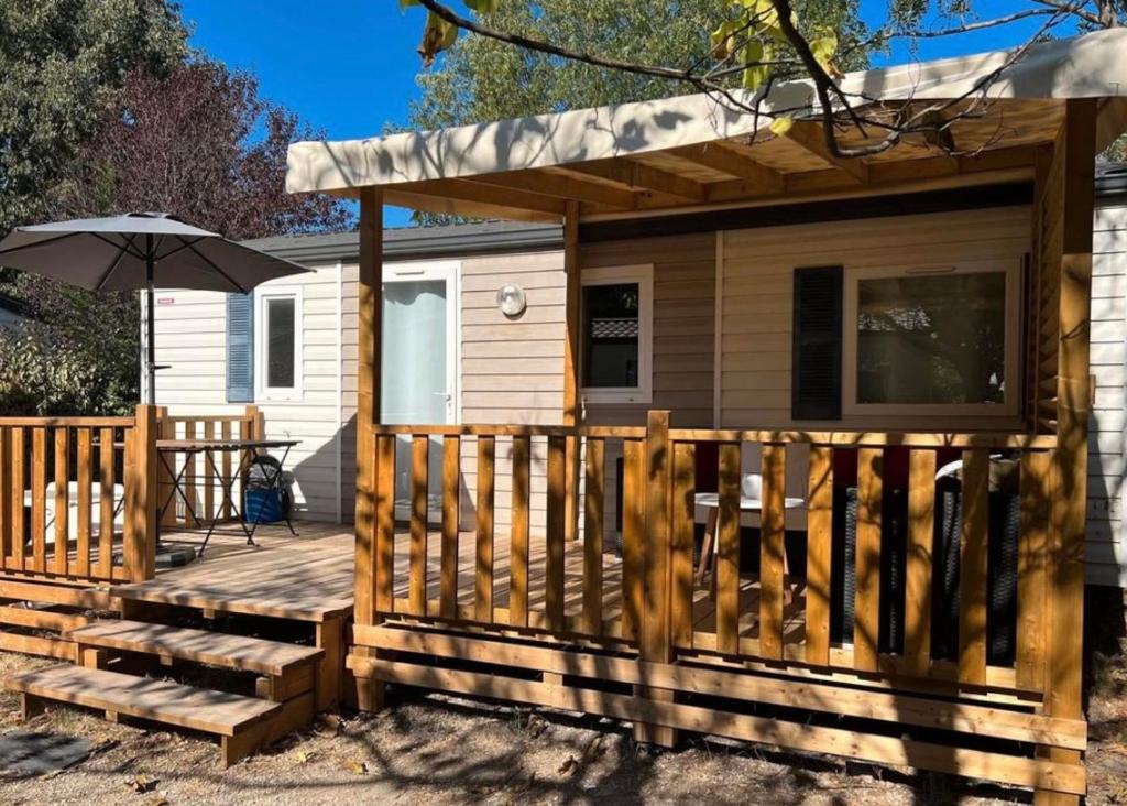 une cabine avec une terrasse et un parasol dans l'établissement Mobil-Home des Iscles, à La Roque-dʼAnthéron