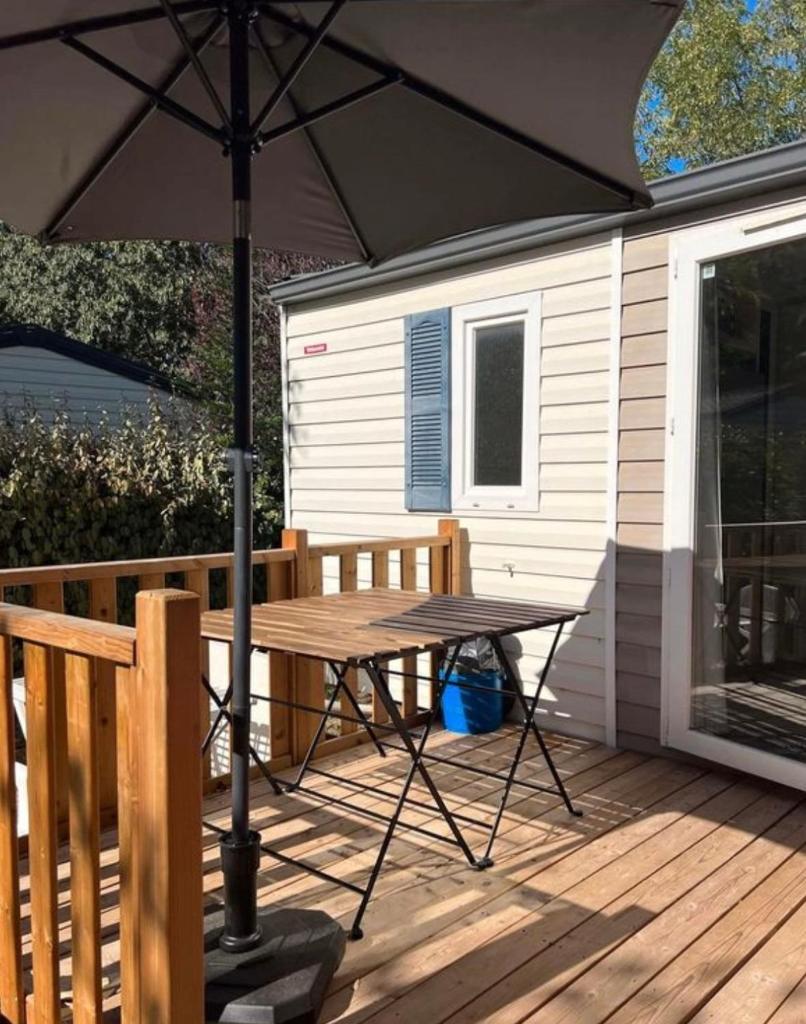 - une table de pique-nique avec un parasol sur une terrasse dans l'établissement Mobil-Home des Iscles, à La Roque-dʼAnthéron