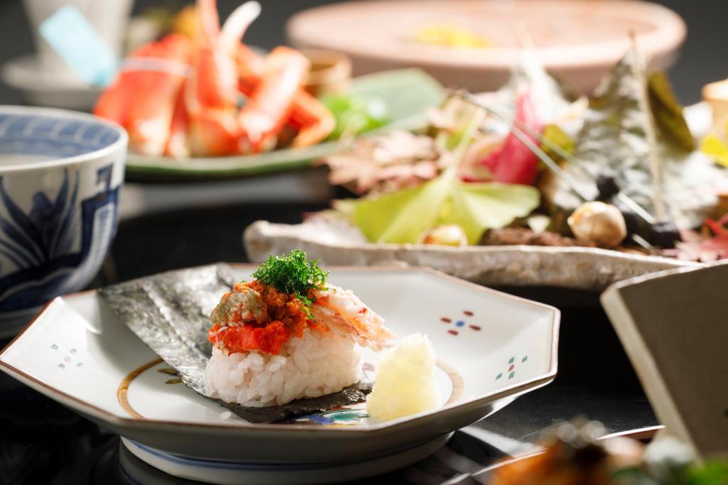 une assiette de sushi sur une table avec d'autres assiettes de nourriture dans l'établissement TAKITEI Riverside Onsen ーA Hidden Ryokan in Kanazawaー, à Kanazawa