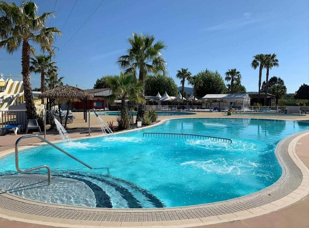 une grande piscine avec de l'eau bleue et des palmiers dans l'établissement Mobilhome L'Estérel du Montourey, à Fréjus