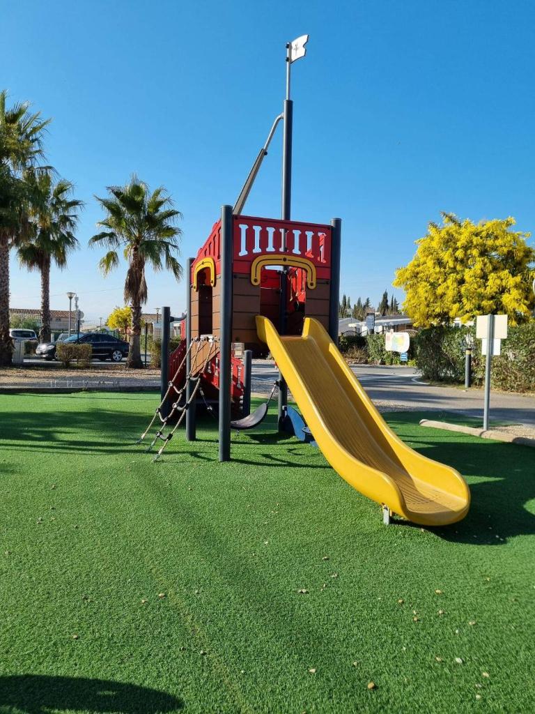 une aire de jeux avec toboggan jaune dans un parc dans l'établissement Mobilhome L'Estérel du Montourey, à Fréjus